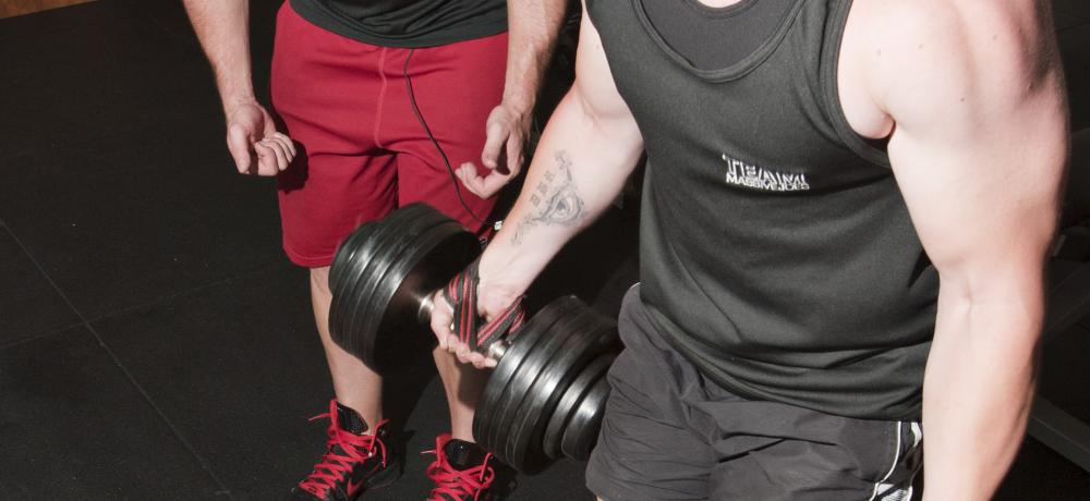 Buddy's Gymnasium's Personal Trainer Joel Bate (left) assists Corporal Callan Metzger, a 16 Ground Liaison Section Physical Training Instructor, in practicing his lifting techniques during a Natural Body Building training sessio