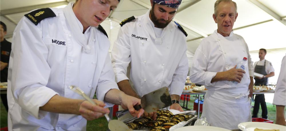 At Claremont Showgrounds, Perth, Able Seaman Maritime Logistics - Chef Phillip Moore, and Leading Seaman Maritime Logistics - Chef Jade Delaporte, plate up the vegetarian meals for the 12th annual Long Table Lunch for Breast Cancer Care - WA under the supervision of Executive Chef Chris Taylor ( Frasers Restaurant