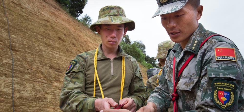 Australian Army soldier, Private Chao Yi (left), learns knot tying before climbing the cliff during Exercise Pandaroo 2017.