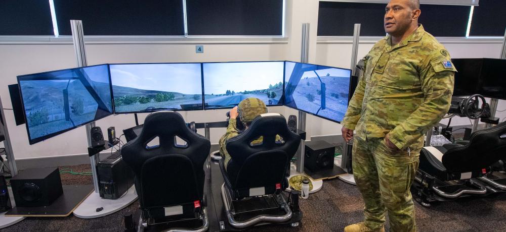 Australian Army Corporal Enele Ma’afu (right), from the 7th Combat Service Support Battalion, supervises his troop while they conduct tactical driver training and Standard Operating Procedure rehearsals using the Virtual Driver Training Simulator at Gallipoli Barracks, Brisbane.