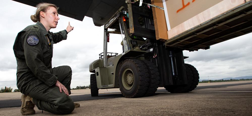 No. 37 Squadron loadmaster Sergeant Brodie Stewart guides a forklift loaded with bundles of livestock fodder onto a C-130J Hercules during an Air Mobility Training and Development Unit trial.