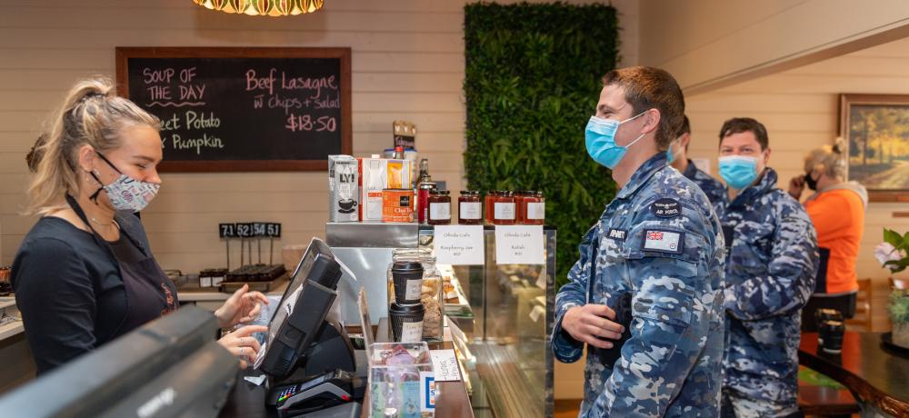 Pilot officer Alex Walsh of the Royal Australian Air Force orders a coffee and food from an Olinda business as he takes a break from his duties assisting the community of Olinda with storm recovery efforts to have some lunch and support the local businesses who are still operating.