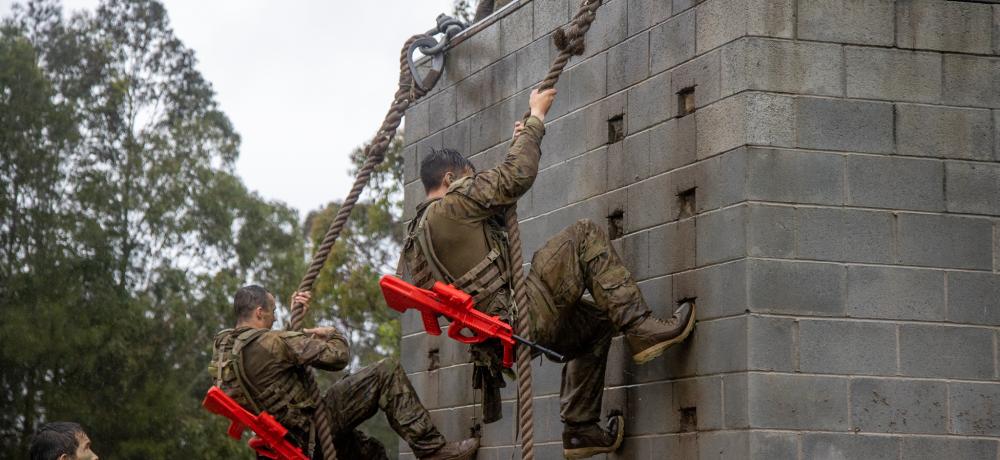 Australian Army soldiers Private Meaham Bailey (left) and Private Bagu Tancredi (right) climb the rope wall as part of Exercise Hardcorps at the School of Infantry, Singleton, New South Wales.