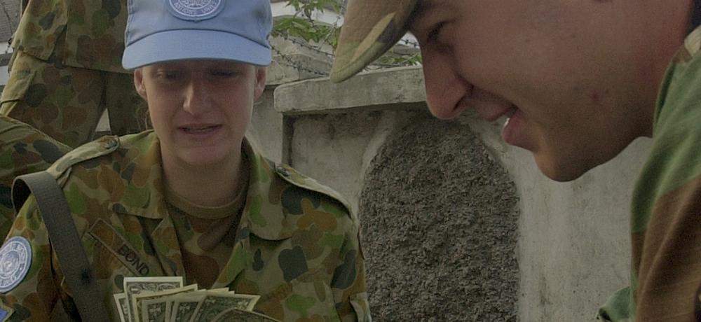 USMC 1st Lieutenant David Vaughan, United States Support Group East Timor, gives ASNCE diggers, from left, Cpl Mark O'Halloran, Sig Gina Bond and RAAF Cpl Allen Weller a soldiers' five on US currency -- East Timor's official currency