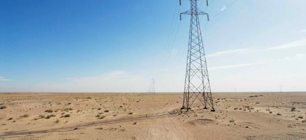 A powerline and dirt track disappear into the distance in the desert