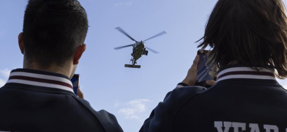 Geelong High School students watch as a Royal Australian Navy MH-60R Seahawk helicopter lands on the school oval during a visit by Royal Australian Navy personnel.