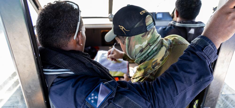 An Australian Army soldier instructs members of the Royal Solomon Islands Police Force on navigation charts during the small boat package of Exercise Coastwatchers 2025, which was held in the Solomon Islands.