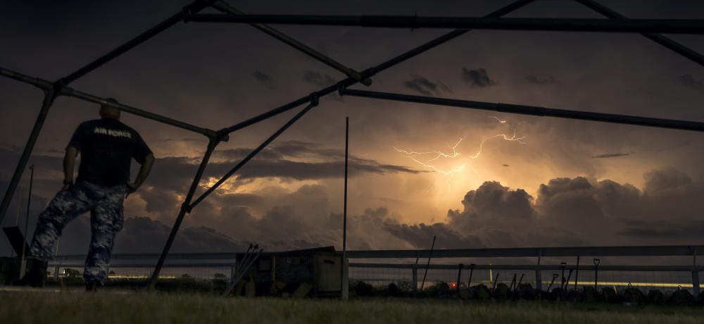 Lightning strikes in the skies surrounding Katherine Showgrounds as Australian Army soldiers from The 5th Battalion, Royal Australian Regiment and Royal Australian Air Force Base Tindal personnel set up emergency shelter tents.