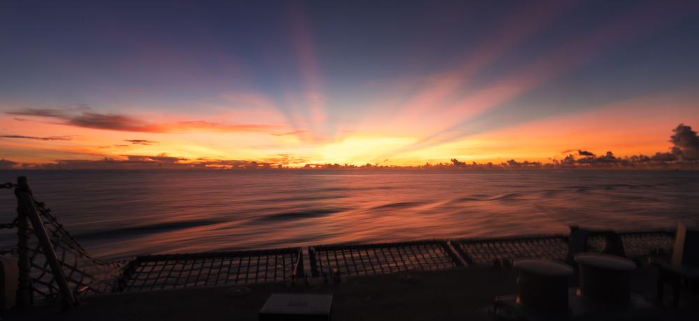 HMAS Brisbane sunset flying operations during a regional presence deployment in the Indo-Pacific.