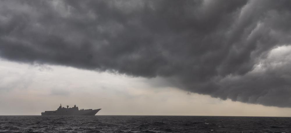 HMAS Adelaide sails into a rain cloud