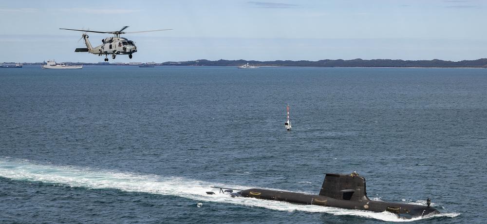 Collins Class submarine heading out to sea from Fleet Base West, shadowed by a  Seahawk 