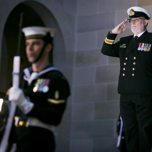 Lieutenant Commander Desmond Woods salutes as the 'Last Post' is sounded at the Australian War Memorial