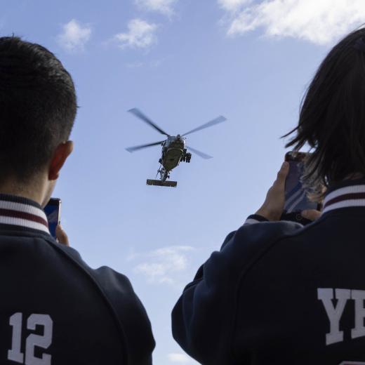 Geelong High School students watch as a Royal Australian Navy MH-60R Seahawk helicopter lands on the school oval during a visit by Royal Australian Navy personnel.