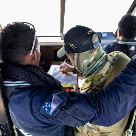 An Australian Army soldier instructs members of the Royal Solomon Islands Police Force on navigation charts during the small boat package of Exercise Coastwatchers 2025, which was held in the Solomon Islands.