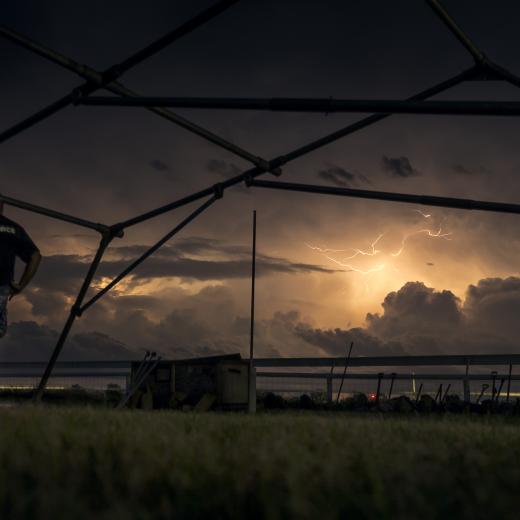 Lightning strikes in the skies surrounding Katherine Showgrounds as Australian Army soldiers from The 5th Battalion, Royal Australian Regiment and Royal Australian Air Force Base Tindal personnel set up emergency shelter tents.