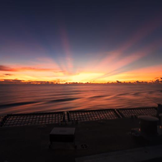 HMAS Brisbane sunset flying operations during a regional presence deployment in the Indo-Pacific.